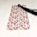 a bookmark with pink flamingos and black tassels