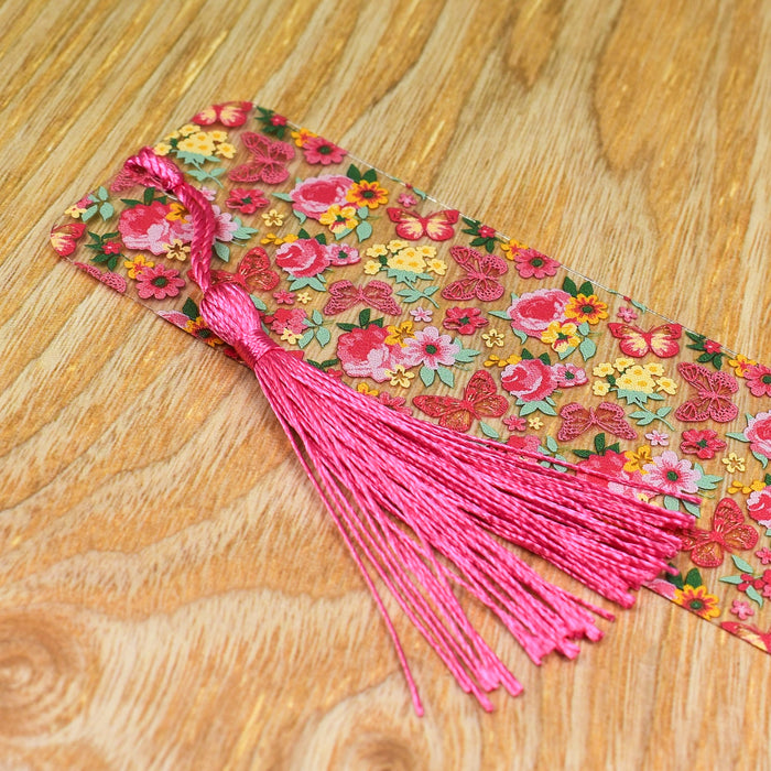 a piece of fabric with pink tassels on a wooden table