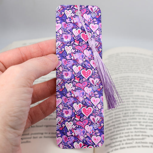 a hand holding a bookmark with hearts on it