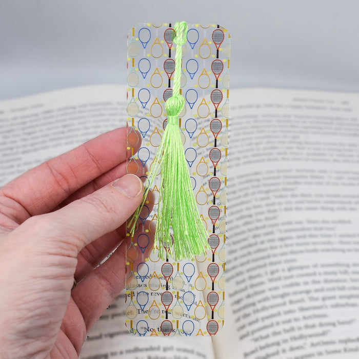 a person holding a bookmark with a tassel on it